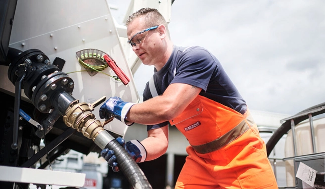 Un dipendente di REMONDIS Italia solleva il tubo flessibile dell'autospurgo utilizzato per smaltire rifiuti pericolosi