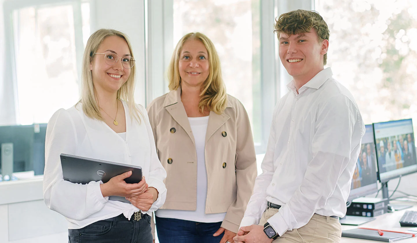 Due donne e un uomo in un ufficio guardano sorridenti l'obiettivo.